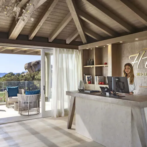 The reception area of 7Pines Resort Sardinia featuring modern design and a welcoming receptionist.