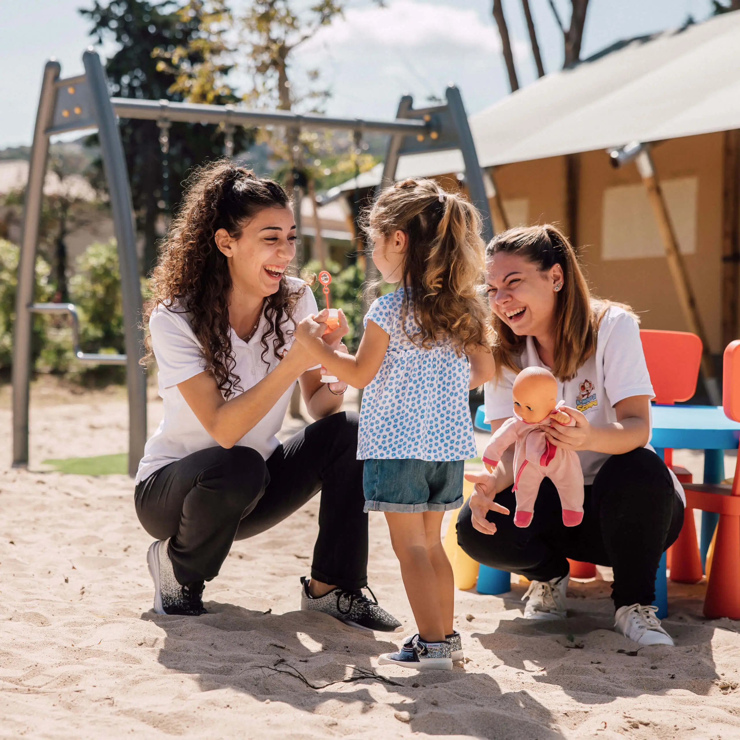 Kinder genießen spielerische Interaktionen mit Betreuern in einem sonnigen Spielplatz.