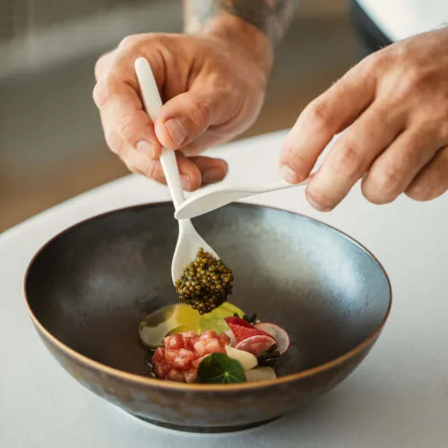 A chef preparing a gourmet dish with caviar at 7Pines Hotels & Resorts.