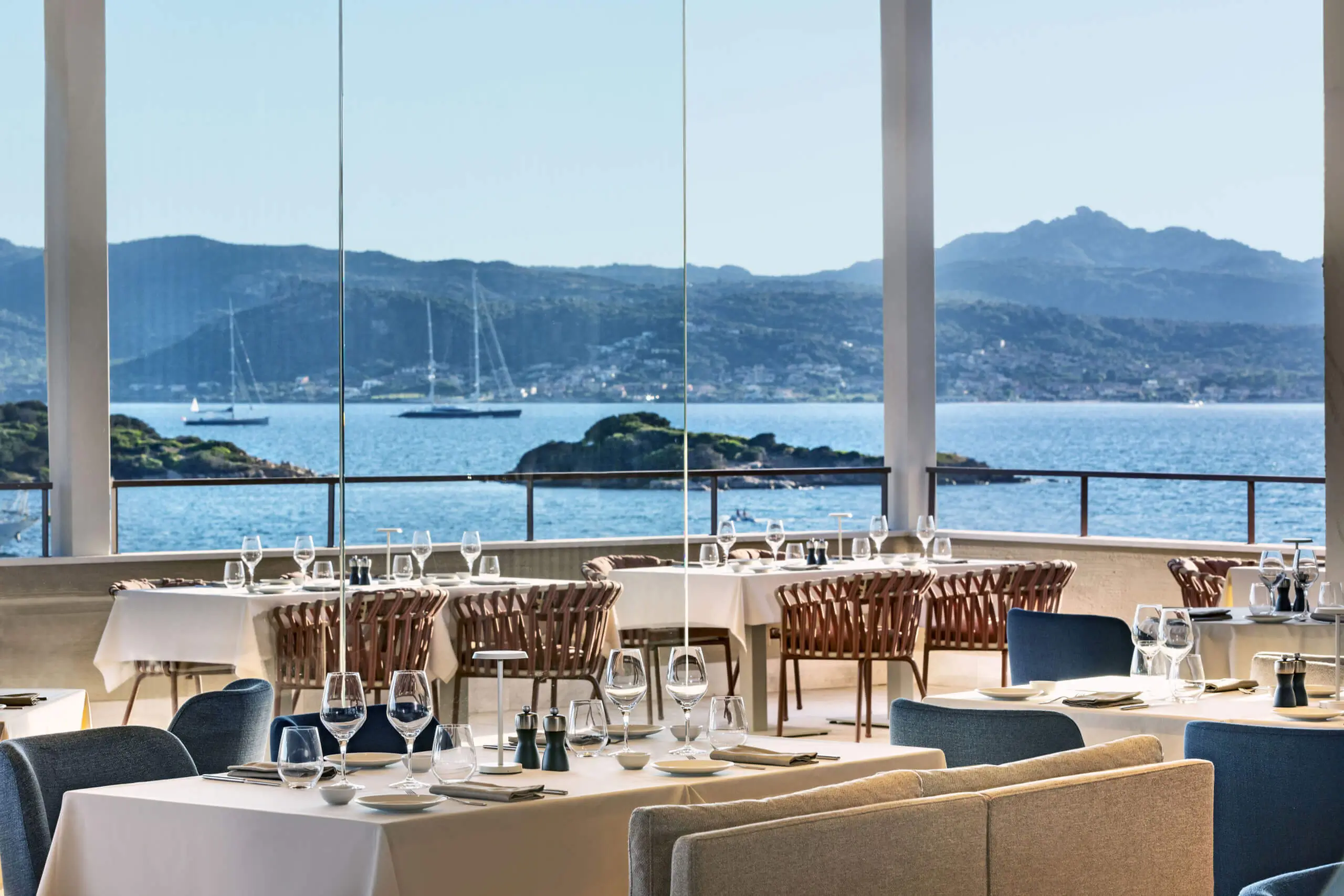 Capogiro fine dining restaurant terrace at 7Pines Resort Sardinia with set tables and panoramic sea views over Baja Sardinia.
