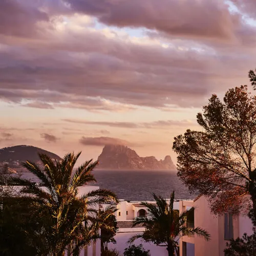 Scenic view of Es Vedrà and palm trees at 7Pines Ibiza Resort.