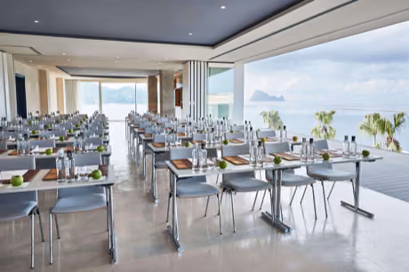 Bright ocean-view meeting room at 7Pines set up for a business event, with conference tables, water bottles and fruit.