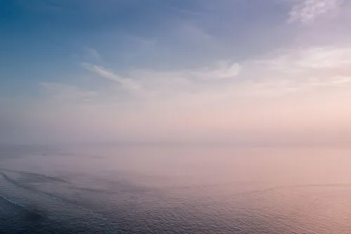 A tranquil ocean view at sunrise with soft pastel colors in the sky.