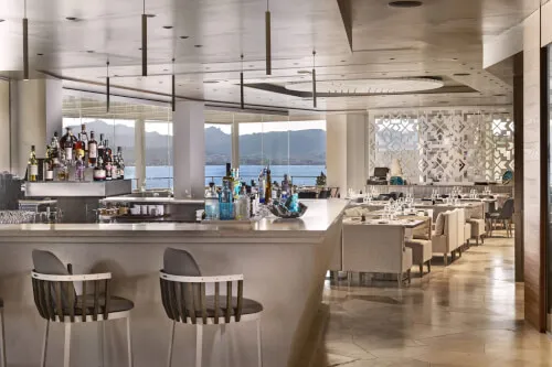 Modern restaurant interior with bar and scenic view at 7Pines Hotels & Resorts.