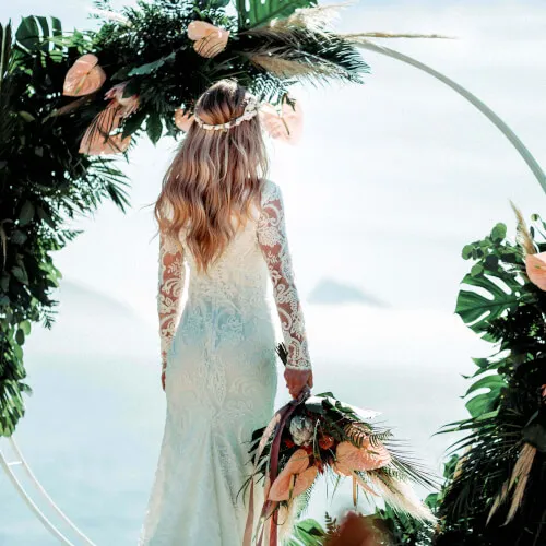 A bride standing in front of a floral arch at 7Pines Resorts, perfect for dreamy weddings.